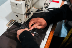 the hands of a tailor working leather on a sewing machine